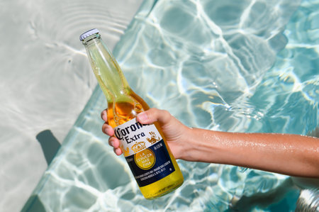 Novorossiysk - Russia, July 2022: A bottle of cold beer Ð¡orona Extra in a woman's hand in the...