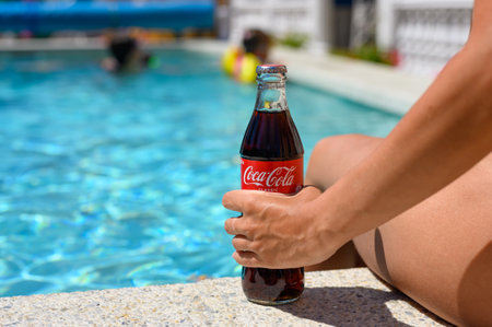 Novorossiysk - Russia, July 2022: A bottle of Coca-Cola in the hand of a girl by the pool on a hot summer day.のeditorial素材