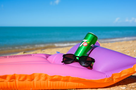 Anapa - Russia, July 2022: Cold drink can 7 up sunglasses on an inflatable mattress on the seashore. Selective focus on a can of drink.のeditorial素材