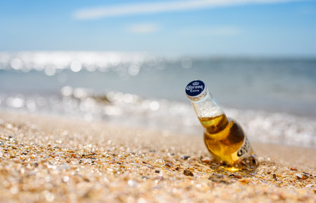 Anapa - Russia, July 2022: A bottle of cold beer Corona Extra on the beach against the backdrop of the glare of the sea. Selective focus on lid with logo.のeditorial素材