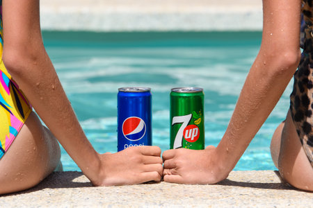 Novorossiysk - Russia, July 2022: Two girls by the pool with cans of cold Pespi Cola and 7up on a summer day. Close-up, view from the backのeditorial素材