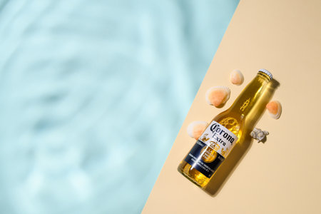 Vladimir - Russia, November 2022: A cold bottle of Corona Extra beer lies on a blue background. Imitation of the pool and the seaのeditorial素材