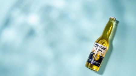 Vladimir - Russia, November 2022: A bottle of Corona Extra beer on a blue abstract background.のeditorial素材
