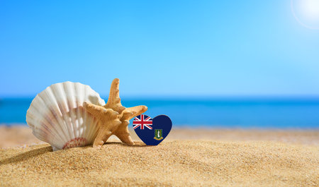 Beautiful beach in the Virgin Islands. Flag of British Virgin Islands in the shape of a heart and shells on a sandy beach.の写真素材