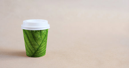 Disposable coffee cup with green leaf texture. The concept of ecology and protection of nature from garbage.の写真素材