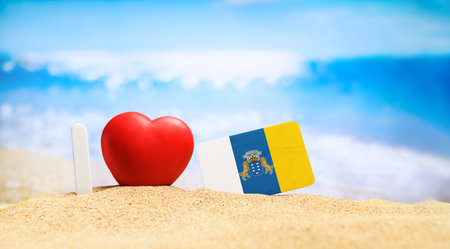 I love the Canary Islands. Flag of the Canary Islands on the beach with a red heart. vacation and travel concept.の写真素材