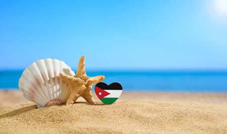 Beautiful beach in Jordan. Flag of Jordan in the shape of a heart and shells on a sandy beach.の写真素材