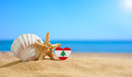 Beautiful beach in Lebanon. Flag of Lebanon in the shape of a heart and shells on a sandy beach.の写真素材