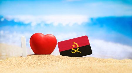 Flag of Angola on the beach with a red heart. vacation and travel concept.の写真素材