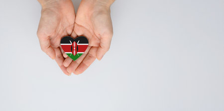 The national flag of Kenya in the shape of a heart of arms in female hands. Flat lay, copy space.の写真素材
