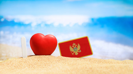 I love Montenegro. Flag of Montenegro on the beach with a red heart. vacation and travel concept.の写真素材