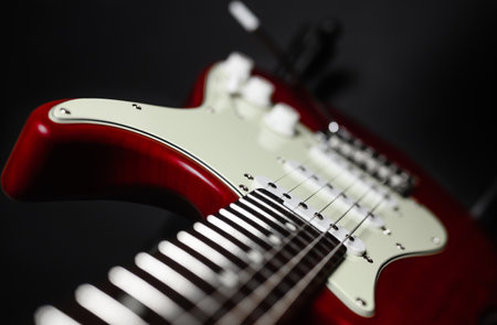 Close-up of a red electric guitar on a black background. Selective narrow focus on pickup.の写真素材