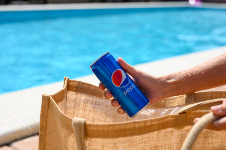 Anapa, Russia - July 23, 2023: The girl at the pool takes out a can of cold Pepsi Cola from her bag.のeditorial素材