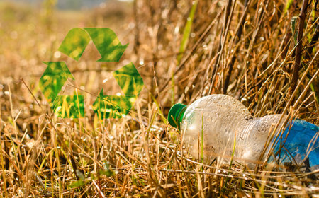 Recycling sign next to plastic trash on nature. The concept of abandoning plastic and using biodegradable materials.の写真素材