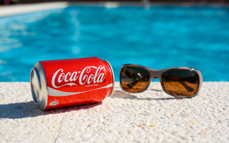 Anapa, Russia - July 18, 2023: Drink Coca Cola and sunglasses on the edge of the pool on a hot sunny day. Close-up, selective focusのeditorial素材