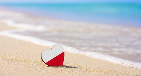 Flag of Poland in the shape of a heart on a sandy beach. The concept of holidays in the resorts of Polandの写真素材