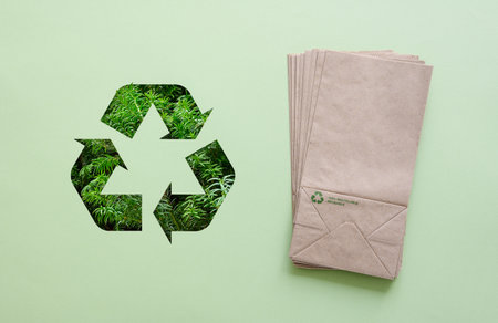 Paper eco-friendly bags and a large recycling sign on a green background. Eco-friendly and zero...