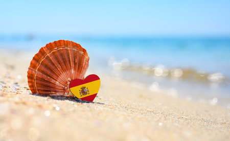 Sandy beach in Spain. Flag of Spain in the shape of a heart and a large shell. A wonderful seaside...