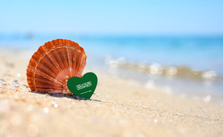 Sandy beach in Saudi Arabia. Flag of Saudi Arabia in the shape of a heart and a large shell.