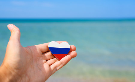Flag of Russia in hand against the sea. Summer vacation in Russiaの写真素材