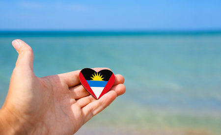 Flag of Antigua and Barbuda in hand against the sea.の写真素材