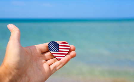 American flag in hand with sea in background. Summer vacation in United Statesの写真素材