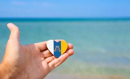 Flag of Canary Islands in hand against the sea. Summer vacation in Canary Islandsの写真素材