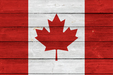 Canada flag on an old wooden surface with cracked paint.の写真素材
