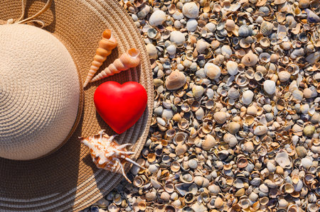 A heart on a straw hat and shells on the beach. A concept of caring for nature.の写真素材