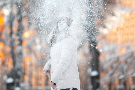 Young teen girl cleans snow near the house, holding a shovel and paddle spend timeの写真素材