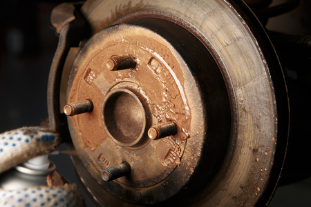 car mechanic cleaning car wheel brake disk from rust corrosion at automobile repair service stationの写真素材