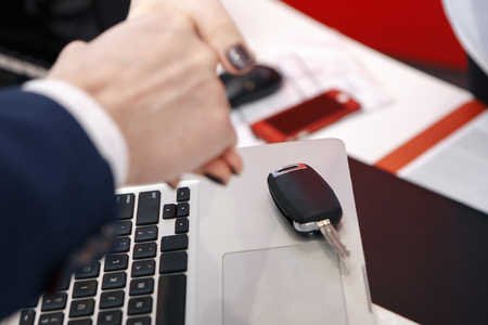Visiting car dealership. Men are shaking hands while signing documentsの写真素材