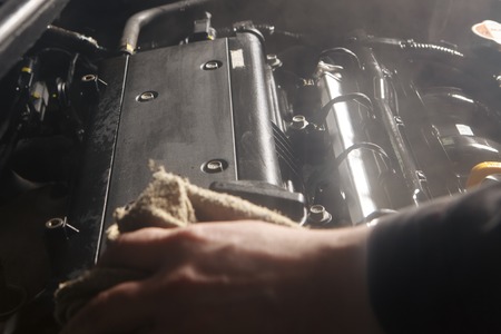 Wipe cleaning the car engine with green microfiber clothの写真素材