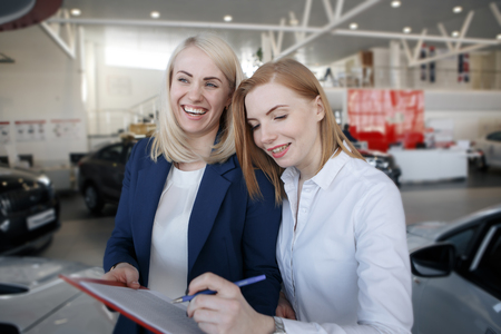 Handsome businessman and auto service mechanic are discussing the work and signing documents. Car repair and maintenance.の写真素材