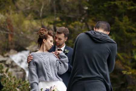 a wedding photographer takes pictures of the bride and groom in nature, the photographer in actionの写真素材