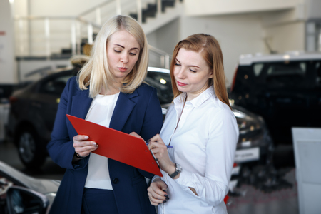 Handsome businessman and auto service mechanic are discussing the work and signing documents. Car repair and maintenance.の写真素材
