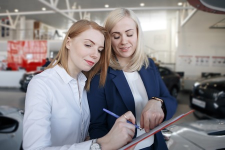 Woman stay a car insurance policy, the agent is pointing at the documentの写真素材
