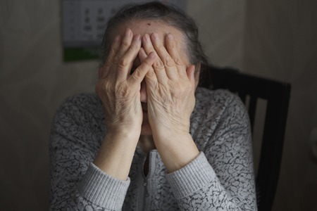 An elderly woman sitting at the table in a depressedの写真素材