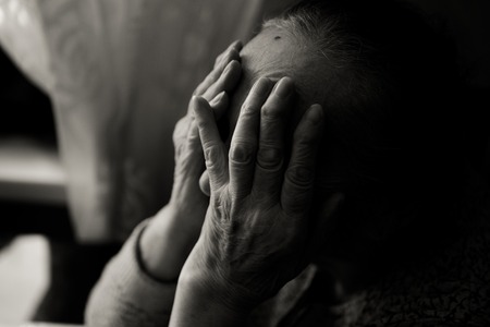 An elderly woman sitting at the table in a depressed state, black and white photo bwの写真素材