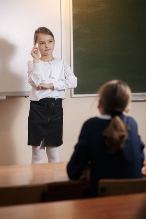 Smiling elderly teacher near the chalkboard asking student at the math lessonの写真素材