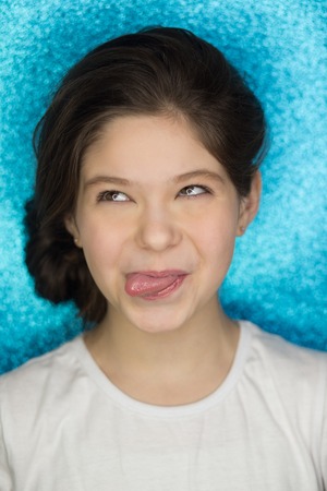 Young pretty sexy girl going crazy alone, blue mint background. showing long tongue, close her eyes, cheekyの写真素材