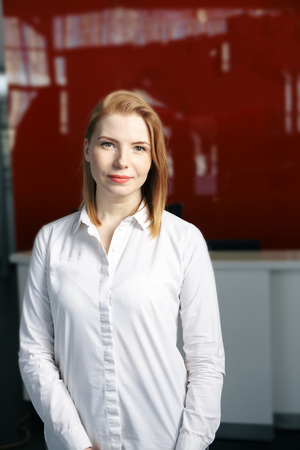 Attractive blonde female office manager supervising working process in office coordinating staff and preparing reporting on conference standing in modern studio with wirelessの写真素材