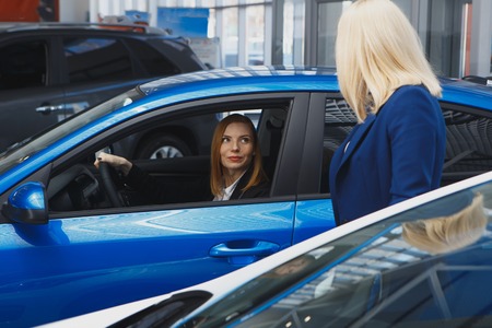 Young smiling woman getting keys of a new car. Concept for car rentalの写真素材
