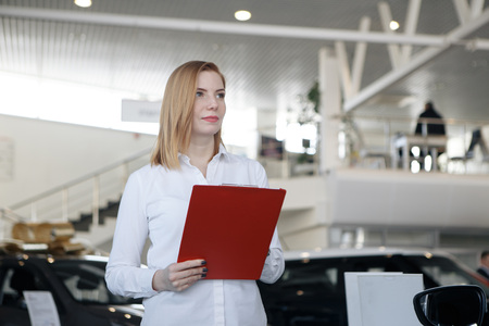 Business meeting. Happy girl is buying new house, young bearded attractive brunet lawyer in a formal wear is presenting contract to sign, they are in his officeの写真素材