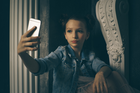Teen girl excessively sitting at the phone at home. he is a victim of online bullying Stalker social networksの写真素材
