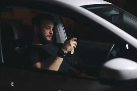 Man drink beer while driving at night in the city dangerously, left hand drive systemの写真素材