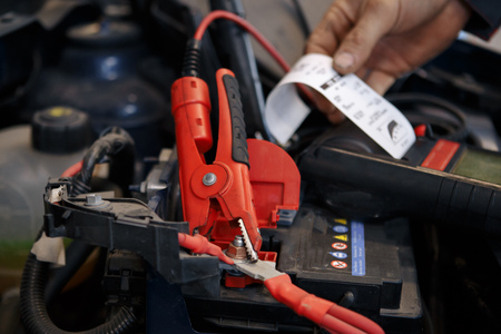 auto mechanic uses multimeter voltmeter to check voltage level in carの写真素材