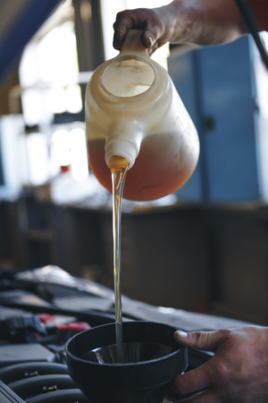 Pouring oil to car engine, close upの写真素材