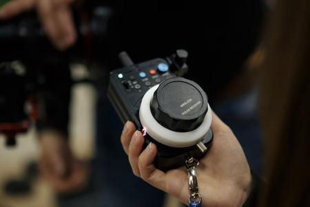 Male hands hold the wireless follow focus system during the filming process.