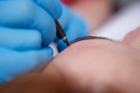 Cosmetologist applying permanent make up on eyebrows- eyebrow